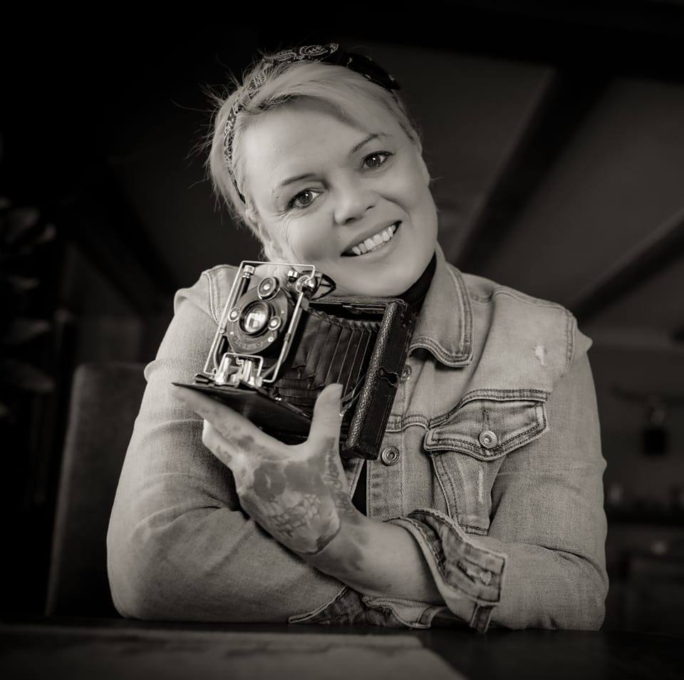 Natalia Nirschl auf einem schwarz weiss Bild mit einer retro Kamera in der Hand.